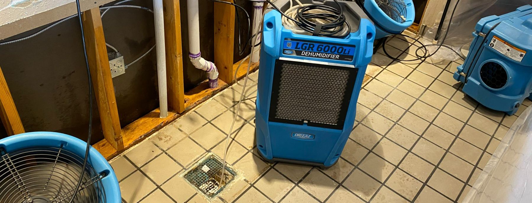 Commercial dehumidifier and air movers drying a room after water damage